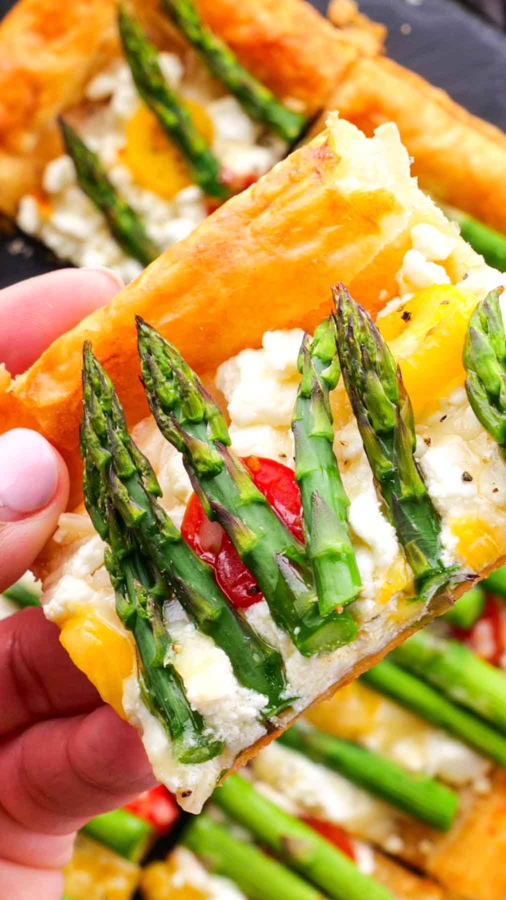 A slice of Asparagus Goat Cheese Tart being lifted, showcasing its colorful toppings.