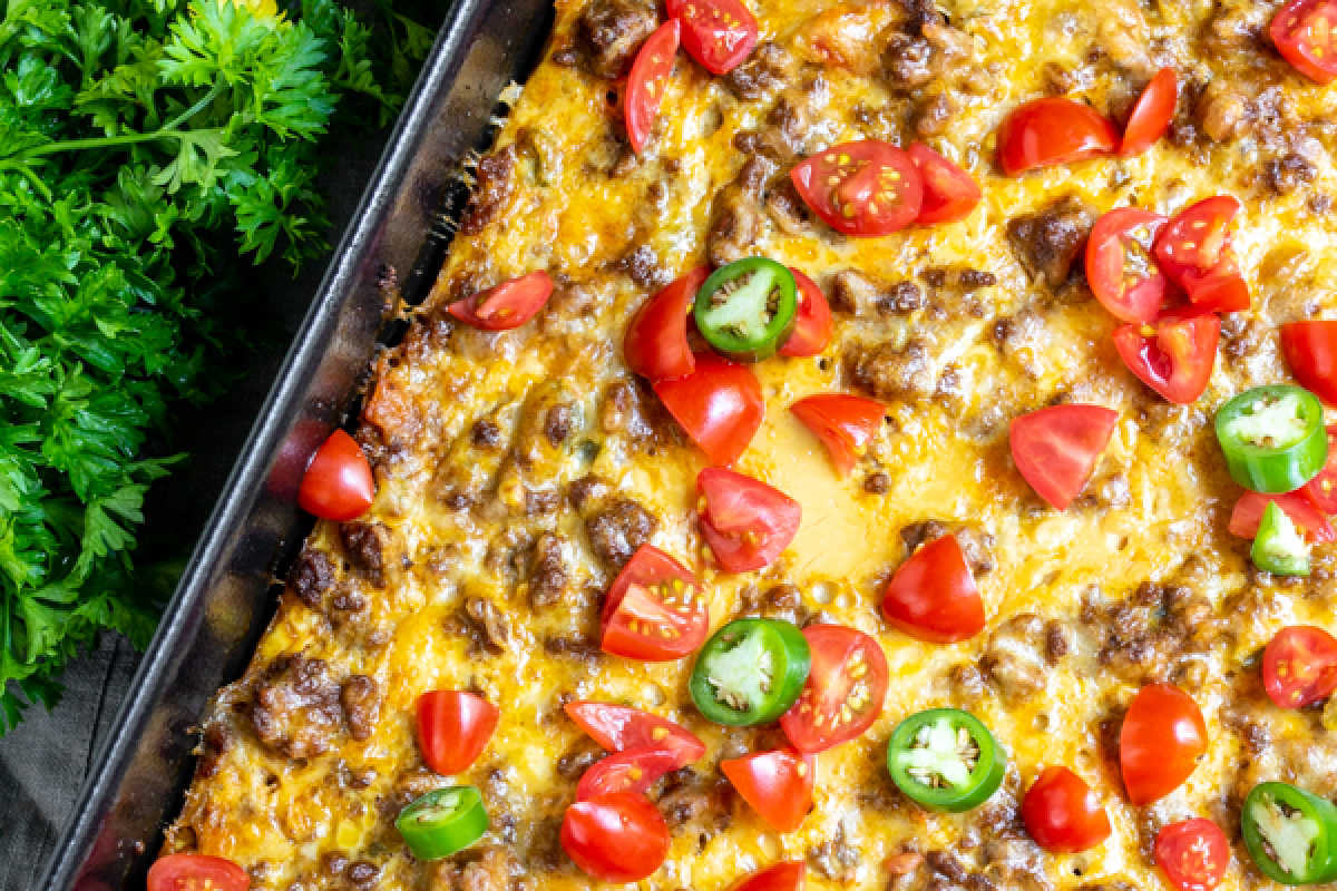 Baked casserole with ground beef, melted cheese, and topped with fresh tomatoes and jalapeño slices.