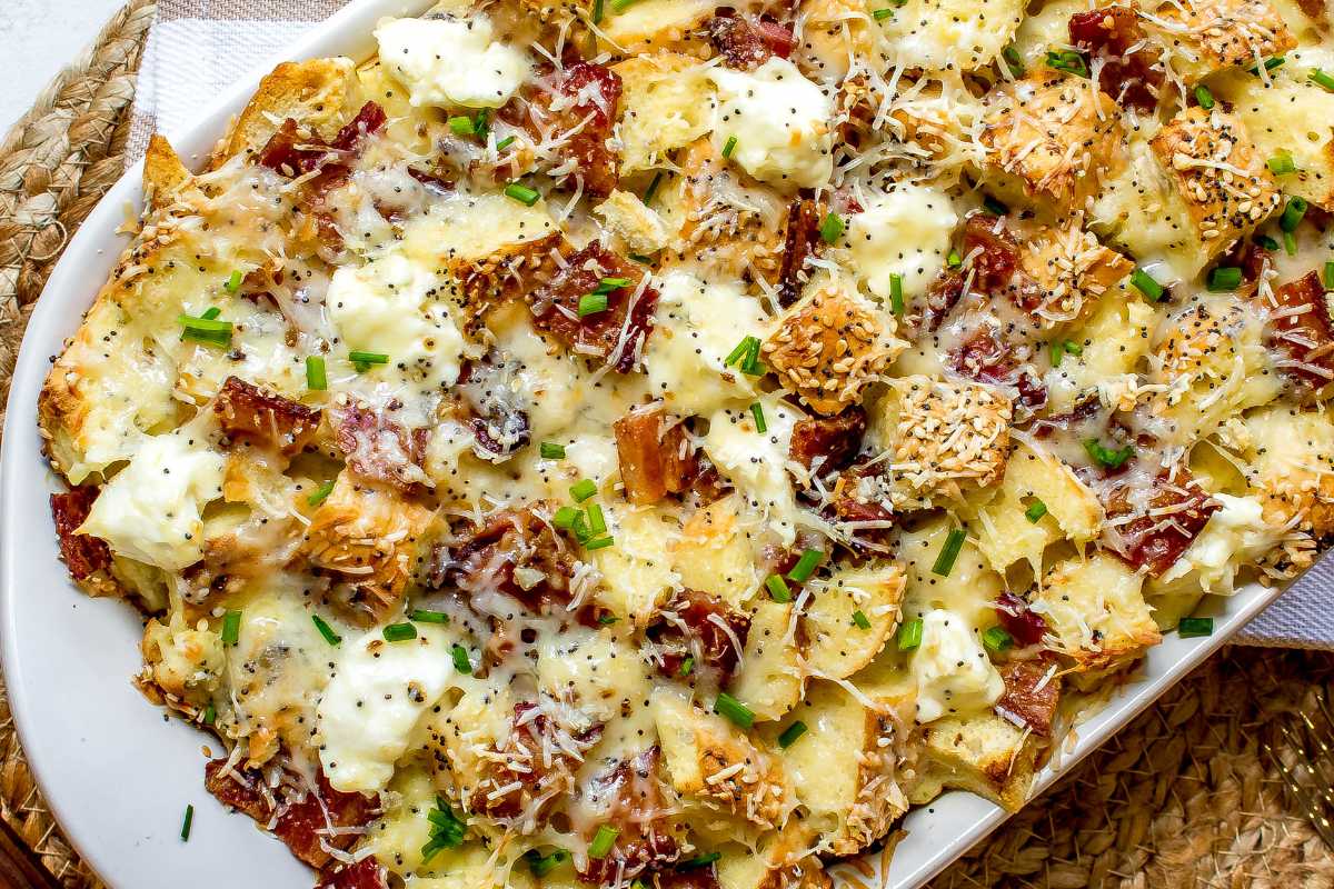 A platter of roasted potatoes topped with melted cheese, bits of crispy bacon, and chopped green onions.