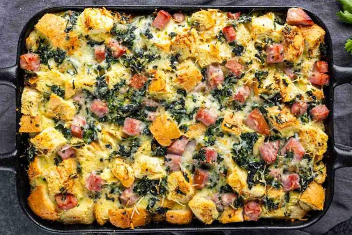 Baked egg casserole with spinach, ham, and diced bread in a rectangular dish.