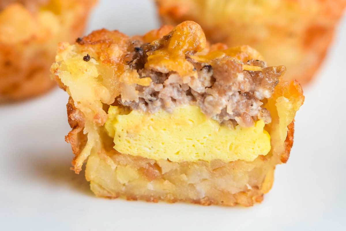 Close-up of a sliced breakfast tater tot showing layers of egg, sausage, and potatoes.