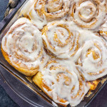 A glass baking dish filled with TikTok cinnamon rolls covered in white icing, viewed from above—a viral and easy cinnamon roll hack using heavy cream for extra softness.
