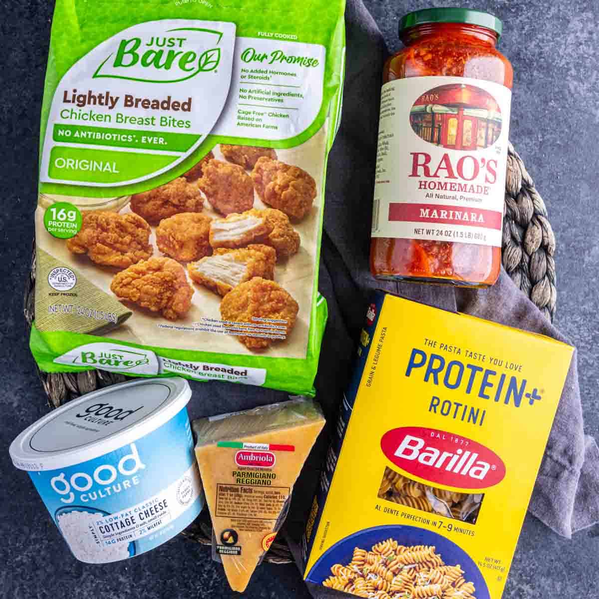 A bag of Just Bare chicken breast bites, Raos marinara sauce, Barilla Protein+ rotini, Good Culture cottage cheese, and parmesan cheese—everything you need for an easy high protein dinner or lunch.