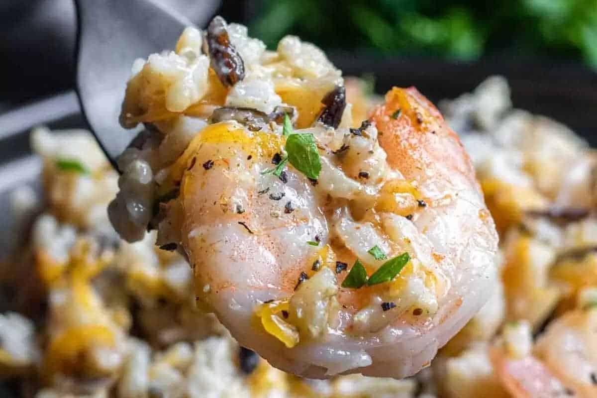 A close-up of a fork holding a shrimp topped with rice, herbs, and spices, with a blurred background of similar food—perfect inspiration for best high-protein recipes or festive New Year recipes.