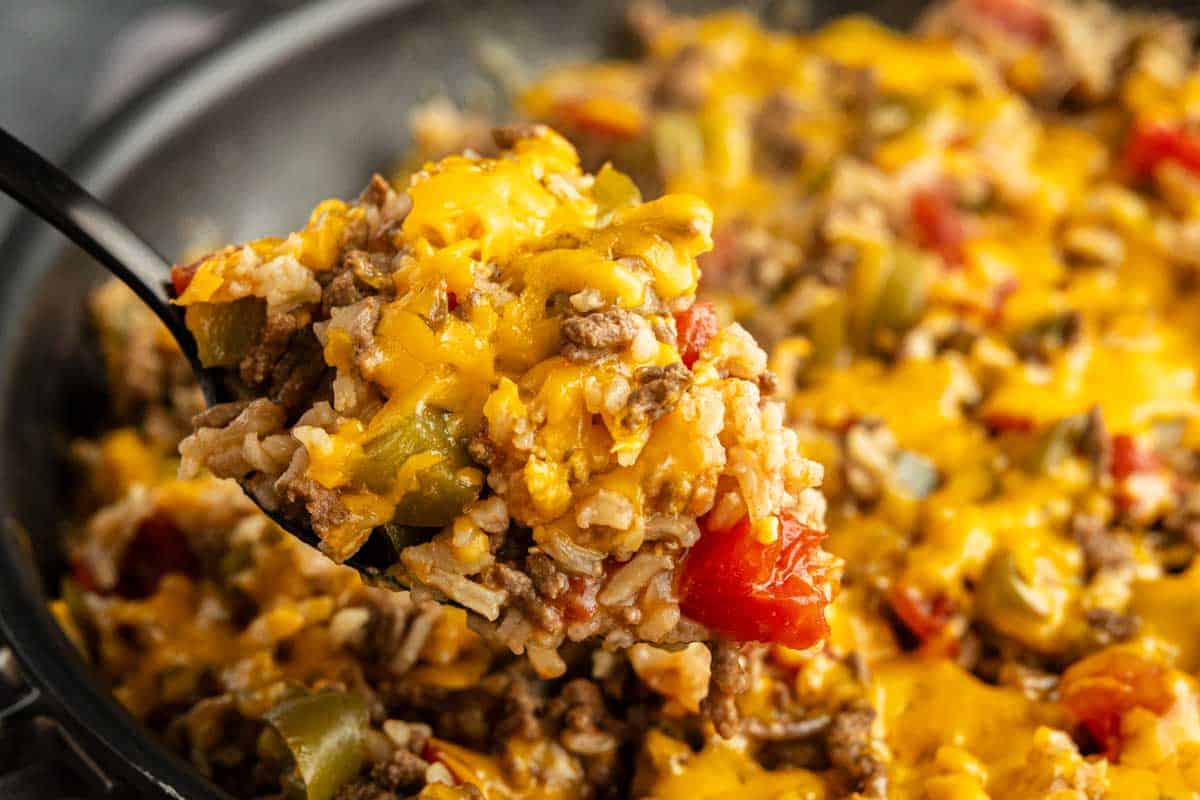 A close-up of a cheesy ground beef and rice skillet with bell peppers and tomatoes, all cooked together for an easy one pan unstuffed peppers meal.