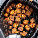 Crispy, seasoned salmon bites cooked in an air fryer basket—perfect for topping a salmon rice bowl or enjoying as a tasty air fryer salmon recipe.