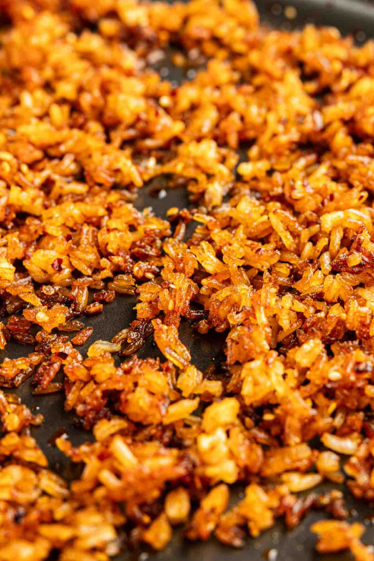 Close-up of golden brown, crispy rice spread out on a dark surface, just like the trending TikTok crispy rice recipe.