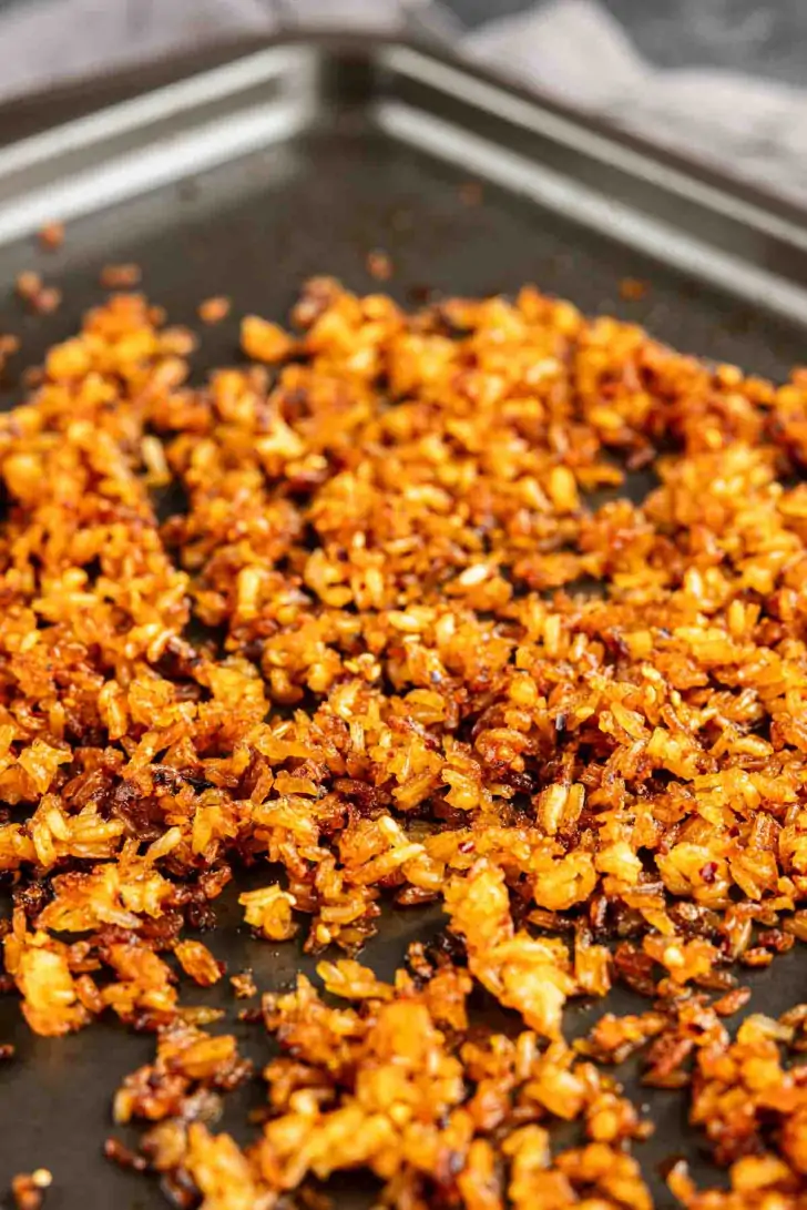 A baking sheet topped with a layer of crispy, golden-brown toasted rice.