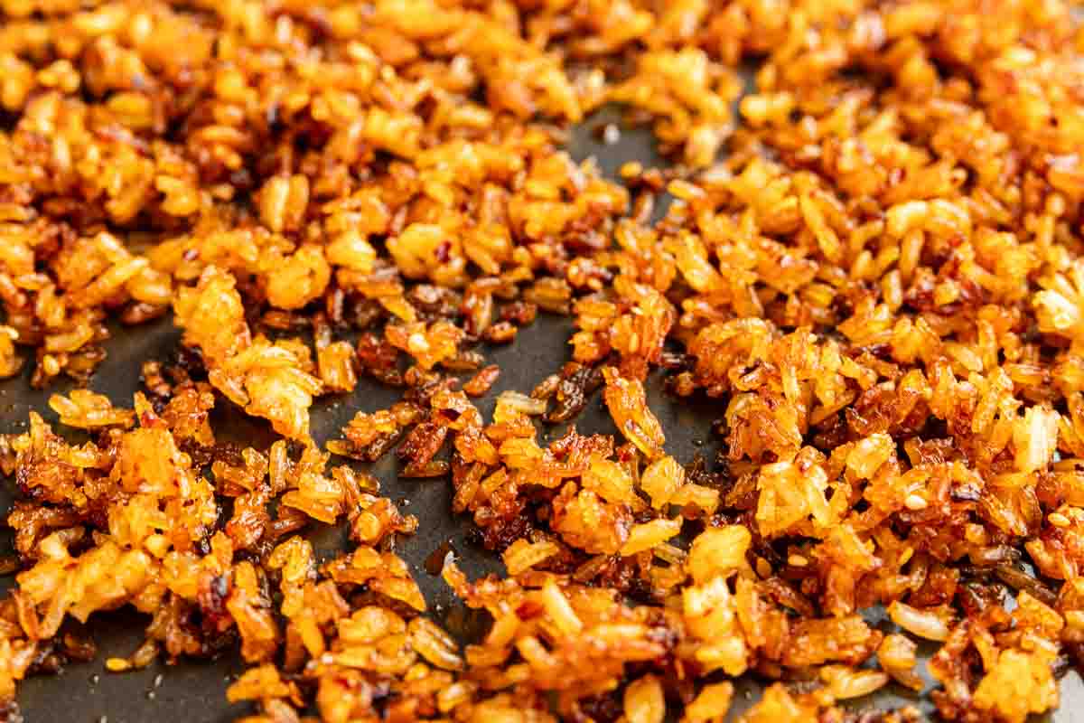 Close-up of golden-brown, TikTok crispy rice scattered on a dark surface.