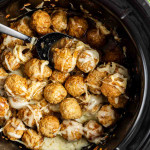 Meatballs topped with melted cheese and flavored with French onion soup mix in a slow cooker, with a serving spoon resting among these easy appetizer meatballs.