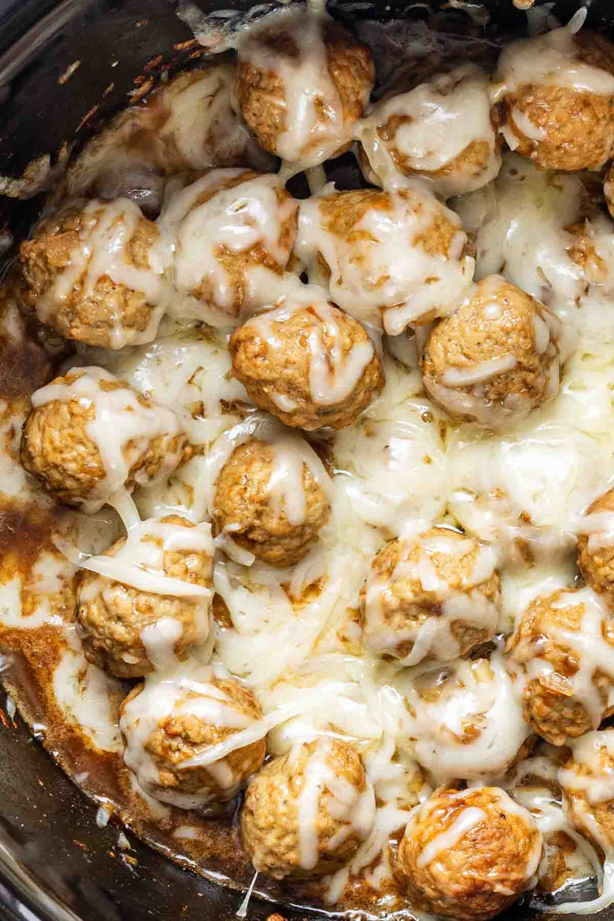Frozen meatballs slow cooker style: cooked meatballs smothered in melted cheese, savory sauce, and a hint of French onion soup mix for an easy appetizer meatballs recipe.