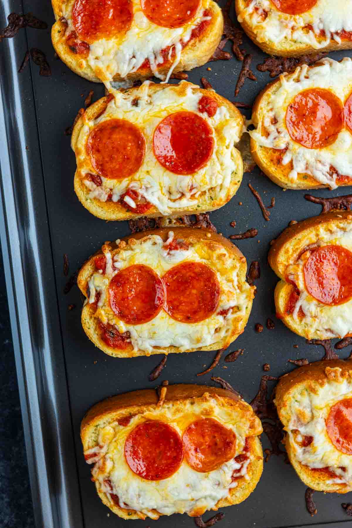 Slices of toasted bread topped with melted cheese, pepperoni, and tomato sauce arranged on a baking sheet—a classic Texas Toast Pizza that's an easy pizza toast recipe for quick weeknight meals.
