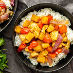 A bowl of white rice topped with chunks of chicken, pineapple, red bell pepper, and red onion in a brown sauce—this easy weeknight dinner is a flavorful one pan Hawaiian chicken recipe the whole family will love.