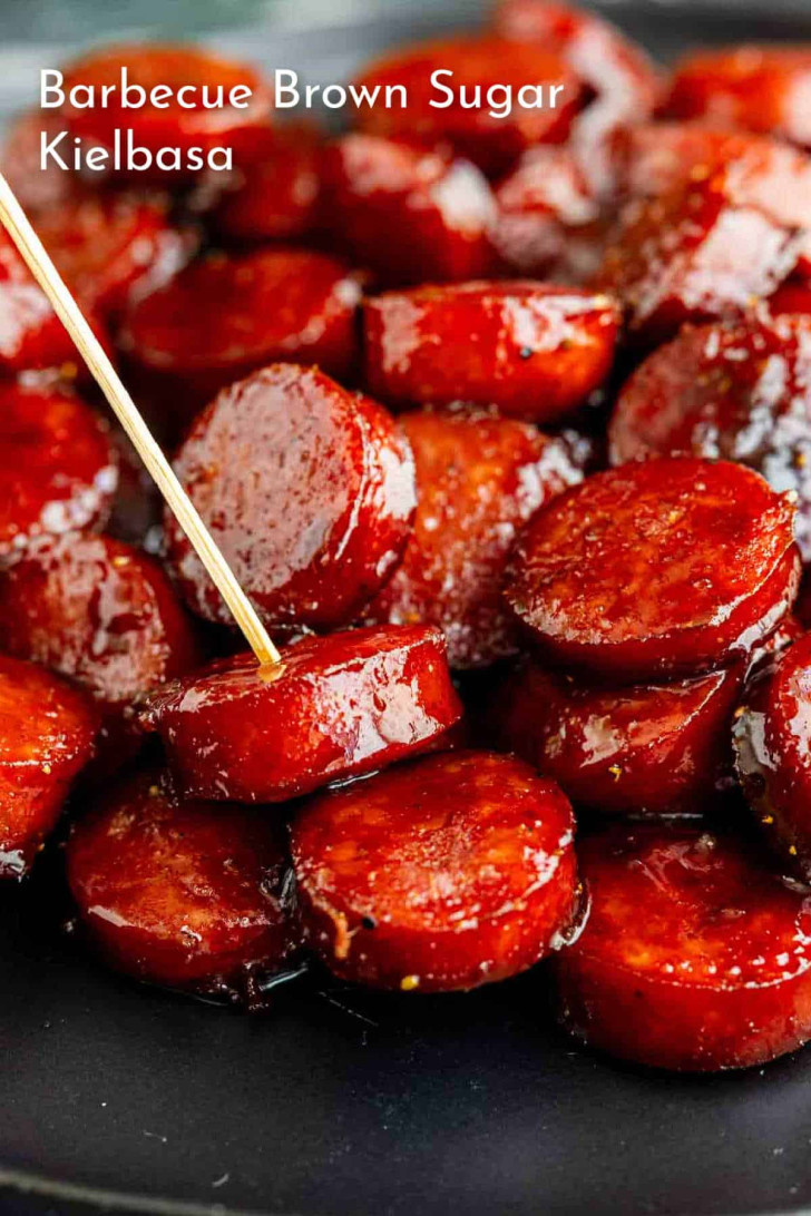 A plate of sliced kielbasa coated in a glossy barbecue brown sugar sauce, with a toothpick inserted into one piece.