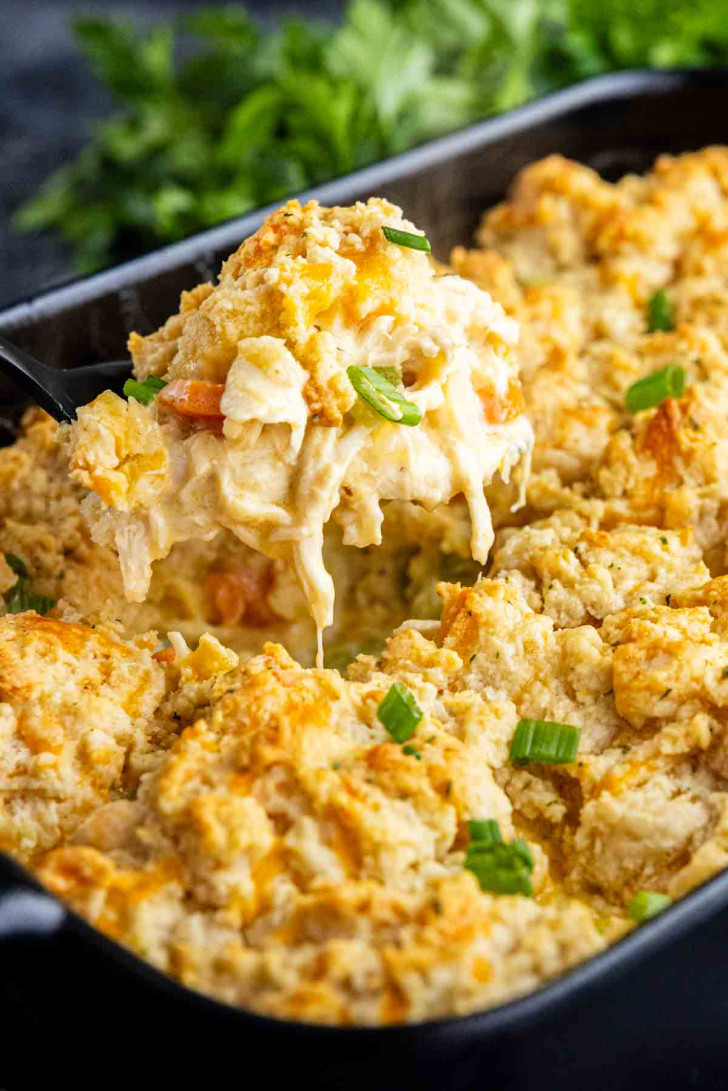 A baking dish filled with creamy chicken biscuit casserole, topped with golden biscuit pieces, reminiscent of a Red Lobster biscuit chicken casserole, and garnished with chopped green onions.