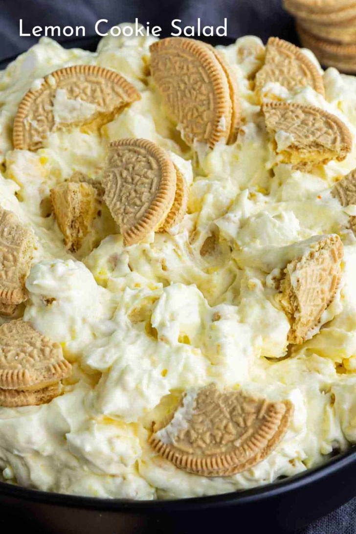 A close-up of a bowl filled with creamy lemon cookie salad, topped with pieces of golden sandwich cookies.