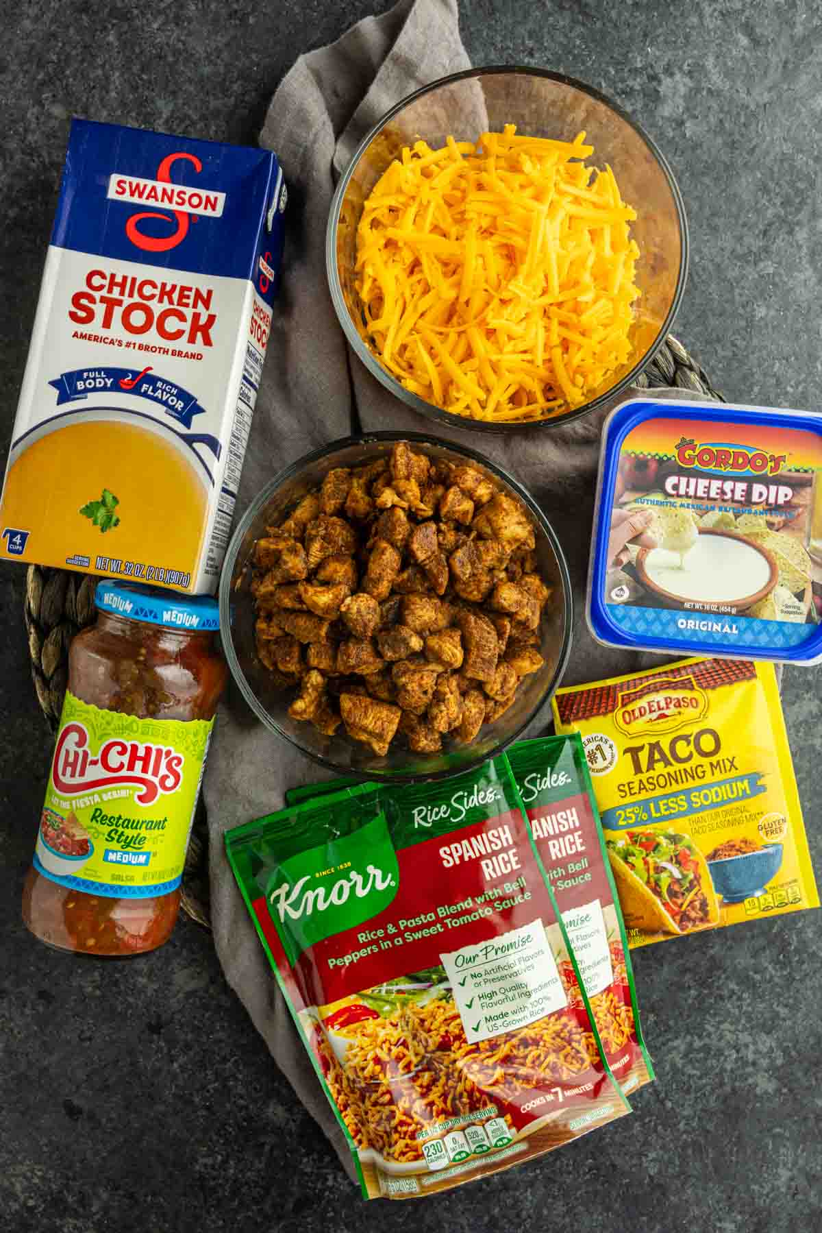 Ingredients for Swim Queso Chicken and Rice including Knorr Mexican Rice, chicken, salsa, cheddar cheese, broth, taco seasoning, and queso.