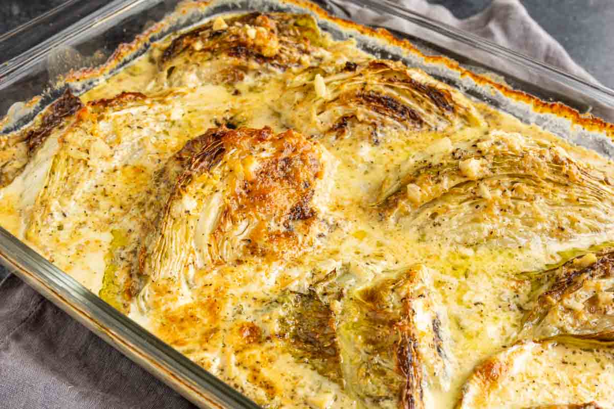 Garlic Butter Melting Cabbage wedges roasted in a creamy sauce in a glass baking dish.