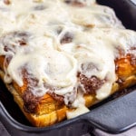A pan of baked Hawaiian sweet roll cinnamon rolls topped with white icing.