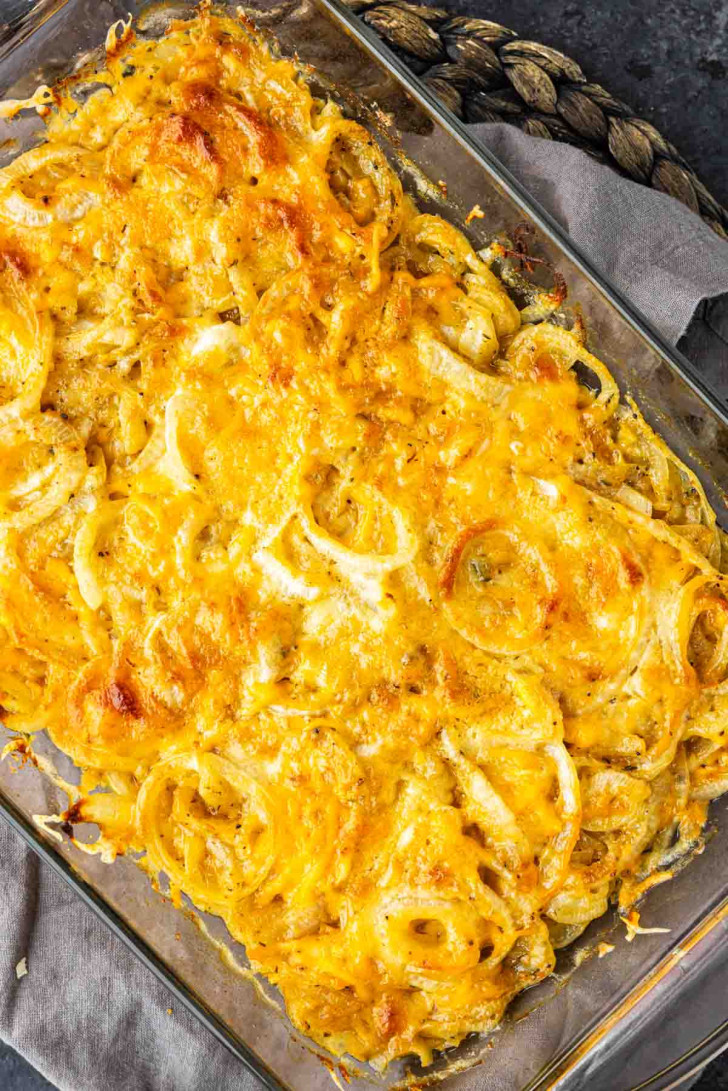 Baked Tennessee onions casserole topped with melted shredded cheese in a glass baking dish.