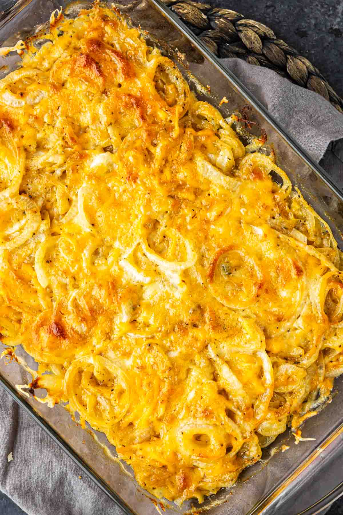 Baked Tennessee onions casserole topped with melted shredded cheese in a glass baking dish.