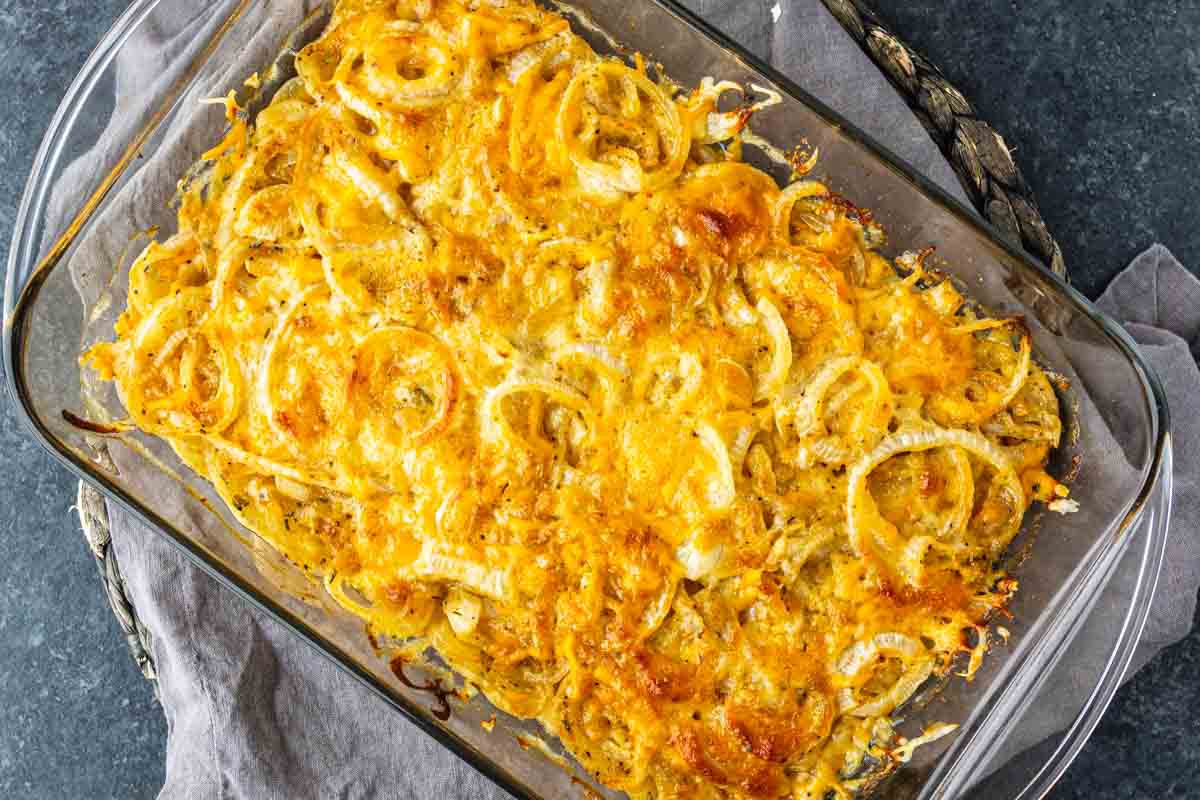 A glass baking dish containing a cheesy onion casserole.